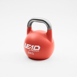 Leadstrong Competition Kettlebell color coded uniform steel bells with a bare unpainted smooth handle lined up on a gym floor.